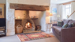 Ein gemütliches Wohnzimmer mit einem Steinkamin, einer bequemen Couch und einem dekorativen Teppich.
