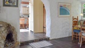 Eine rustikale Küche mit Steinofen, Holzausstattung und einem Essbereich mit Tisch und Stühlen.