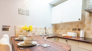Cocina moderna con encimera de madera, armarios blancos y un cartel de 'No Smoking'.