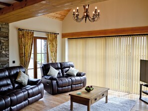 A living room with two leather sofas, a wooden coffee table, and a television.
