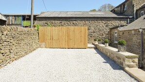 Un bâtiment en pierre avec un toit en tuiles, une porte en bois et un sol recouvert de gravier.