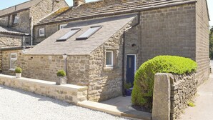 Un bâtiment en pierre avec un toit en pente, une petite porte et une fenêtre.