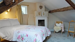 A cozy attic bedroom with a bed, a fireplace, and a wooden ladder. - 1 bedroom accommodation in Combe, near Presteigne (Combe, near Presteigne)