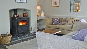 A cozy living room with a fireplace, a sofa, and a coffee table. - 1 bedroom accommodation in Combe, near Presteigne (Combe, near Presteigne)