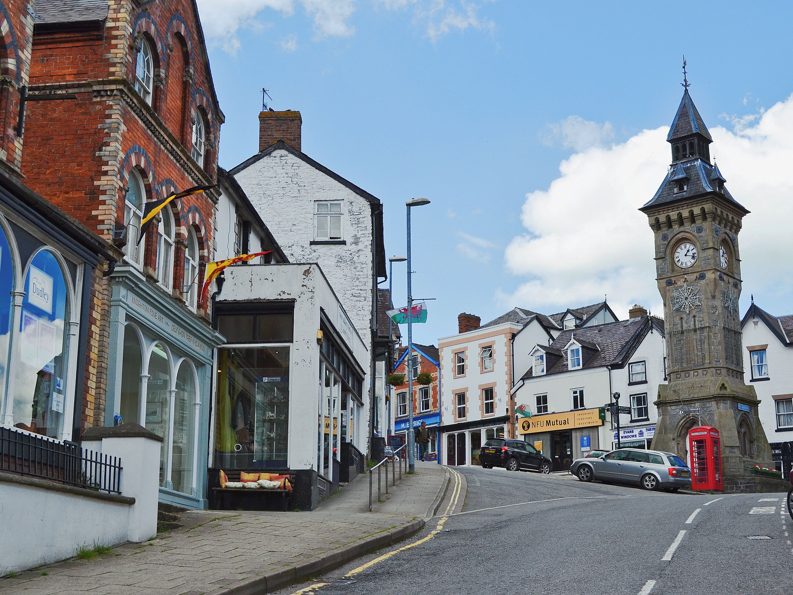 A street with historic buildings, a clock tower, and a red telephone booth.