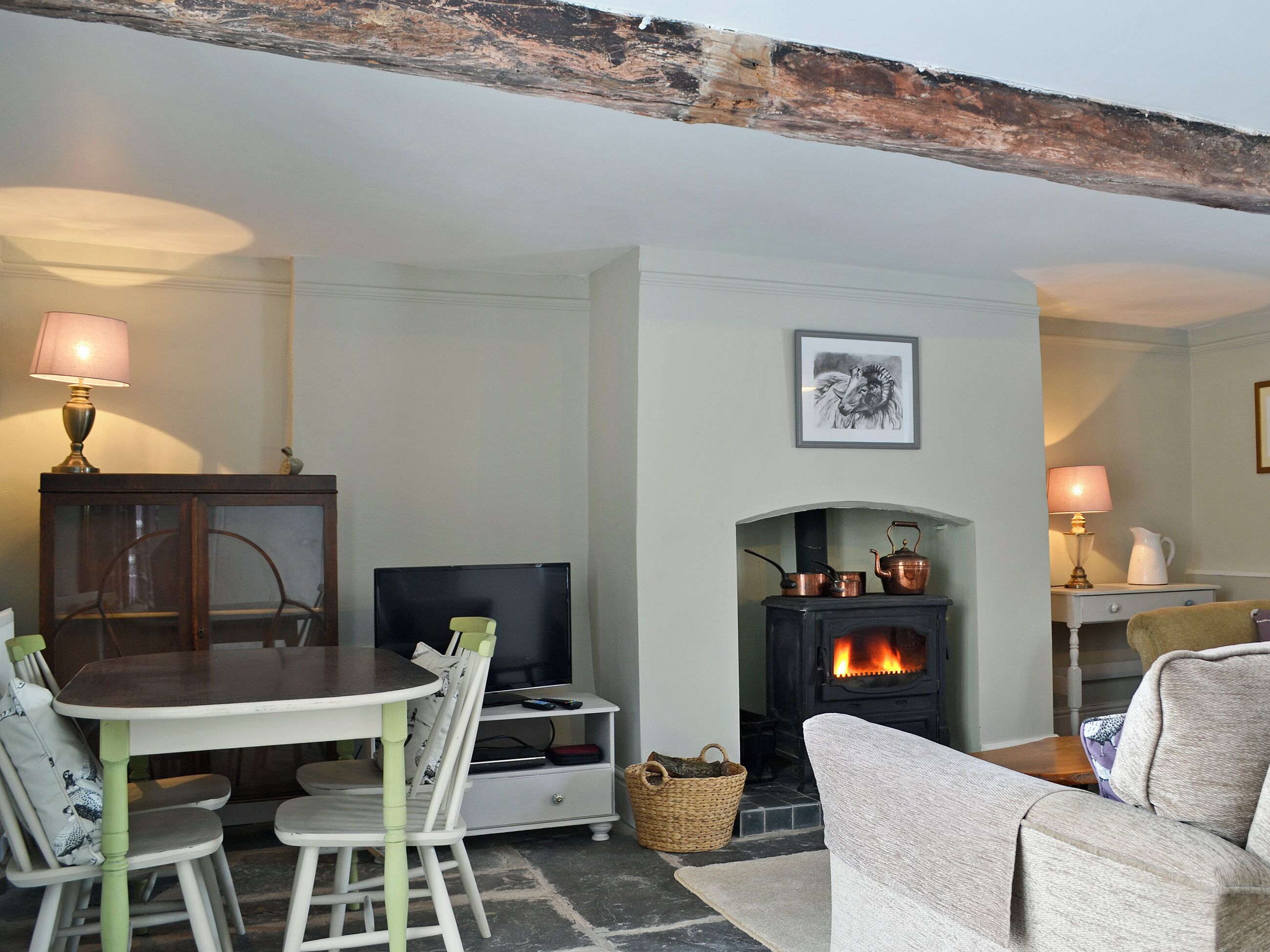 A cozy living room with a fireplace, a dining table with chairs, a television, and a sofa.