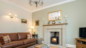 A living room with a fireplace, a sofa, a coffee table, and a television.