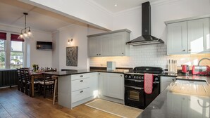 A modern kitchen with white cabinetry, a black stove, and a dining area with wooden chairs.