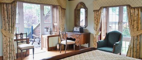 A bedroom with a bed, a desk, two chairs, a dresser, and a large mirror.