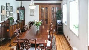 A dining room with a long wooden table, chairs, a chandelier, framed pictures on the wall, and a potted plant. - 4 bedroom accommodation in Webbery, near Bideford (Webbery, near Bideford)