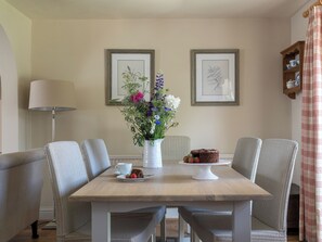 A dining area with a table, chairs, a vase of flowers, a cake, and framed botanical prints on the wall. - 3 bedroom accommodation in Pickering (Pickering)