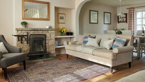 A living room with a fireplace, a sofa, a chair, and a dining area with a table and chairs.