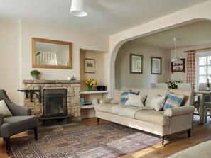 A living room with a fireplace, a sofa, a chair, and a dining area with a table and chairs. - 3 bedroom accommodation in Pickering (Pickering)