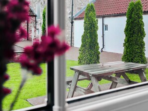 Vista de un patio con una mesa de madera y dos árboles altos y delgados.