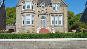 A historic stone building with a central entrance, a bay window, and a turret. - 4 bedroom accommodation in Millport, Isle of Cumbrae (Millport, Isle of Cumbrae)