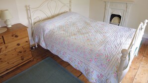 A bedroom with a bed, dresser, and fireplace. - 4 bedroom accommodation in Cilan, near Abersoch (Cilan, near Abersoch)