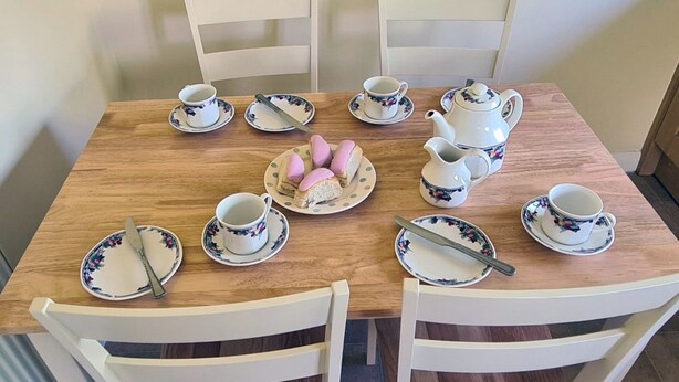 Une table à manger dressée avec de la vaisselle à motifs floraux, comprenant des assiettes, des tasses et une théière.