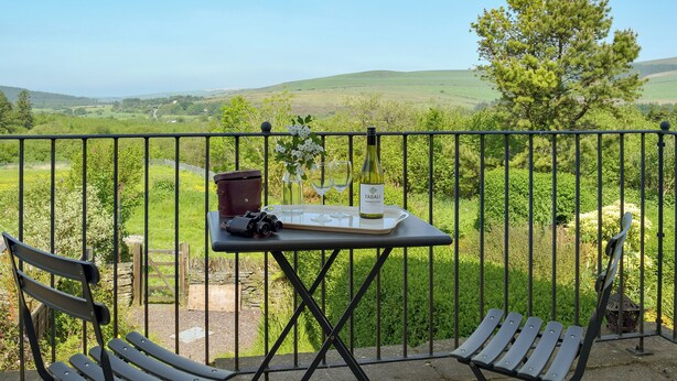 Ein Balkon mit Tisch für zwei Personen, einer Kamera und einer Weinflasche.