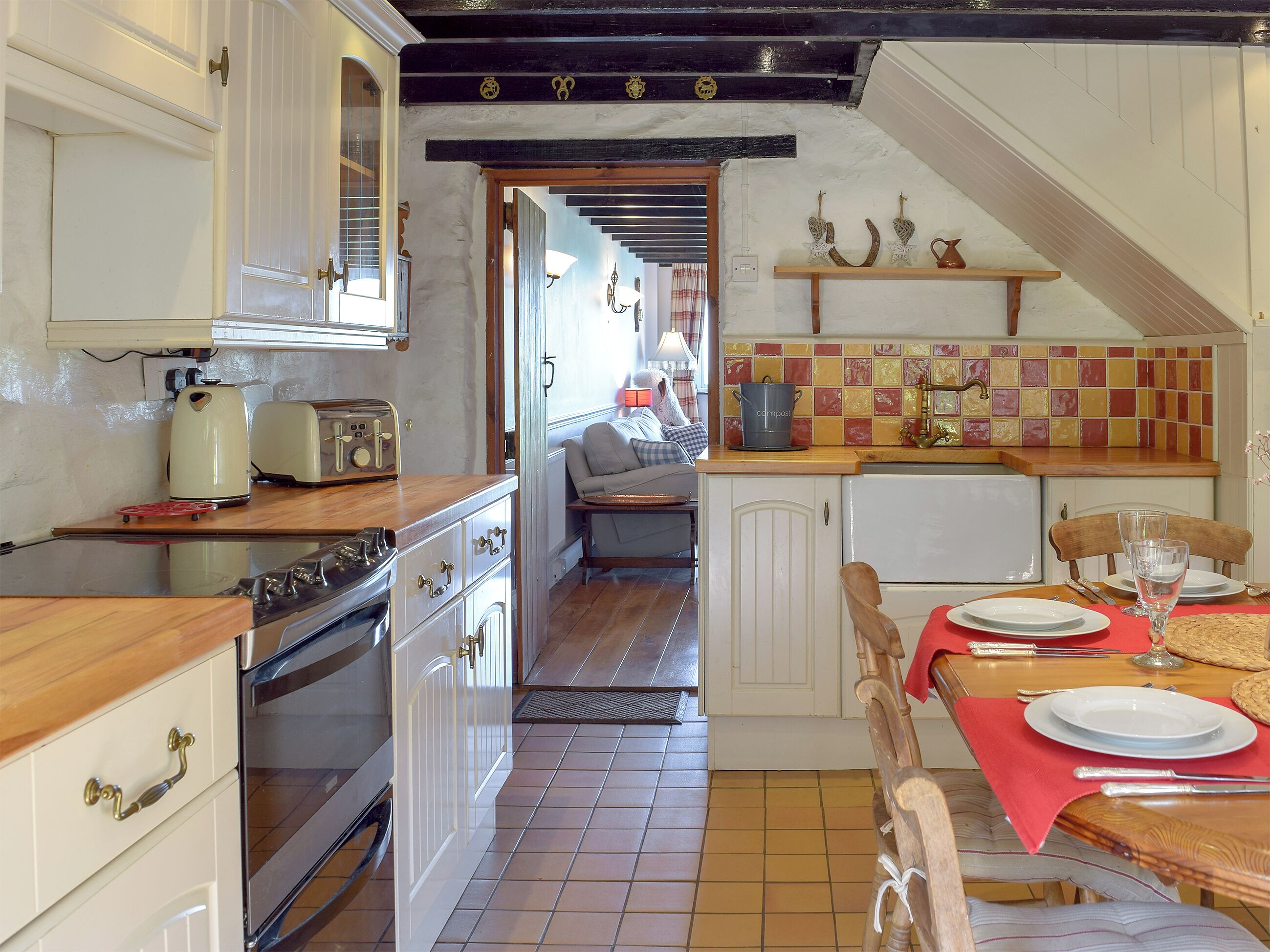 A kitchen with a wooden countertop, a stove, and a dining area with a table set for two.