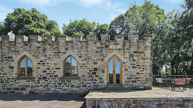 A stone building with arched windows and a brick-paved courtyard.