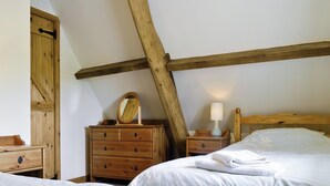 Una camera da letto con due letti, mobili in legno, una cassettiera, uno specchio e una lampada da comodino.
