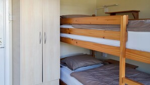 A dormitory room with bunk beds, a wooden wardrobe, and a desk with a lamp. - 2 bedroom accommodation in Dawlish Warren (Dawlish Warren)
