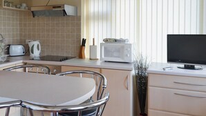 A kitchen with a dining table, chairs, a microwave, a toaster, and a window with blinds. - 2 bedroom accommodation in Dawlish Warren (Dawlish Warren)