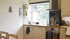 Une cuisine moderne avec des meubles de rangement en bois, un four encastré et une fenêtre donnant sur un jardin.