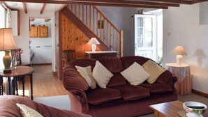 Un salon chaleureux avec un escalier en bois, un canapé rouge et deux lampes.