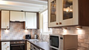 Une cuisine moderne avec des meubles blancs, un four en acier inoxydable, un lave-vaisselle, un four à micro-ondes et une bouilloire.