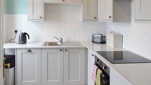 A kitchen with white cabinets, a kettle, a toaster, and a bread box. - 2 bedroom accommodation in Ambleside (Ambleside)