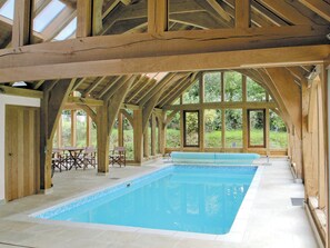 Une grande piscine intérieure dotée d’un plafond en bois et de grandes fenêtres.