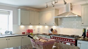 A kitchen with white cabinets, a red stove, and a granite countertop.