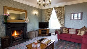 A living room with a fireplace, a television, a plaid carpet, and a red sofa.