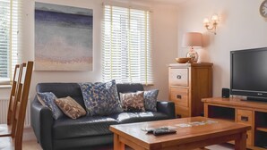 A living room with a sofa, a coffee table, a TV, and a painting on the wall. - The House On The Green (Chipping Norton)