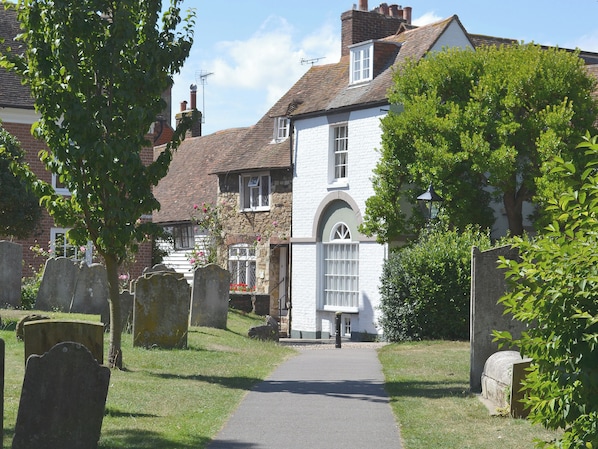A cemetery with headstones and a pathway leading to a white building with a stone facade.