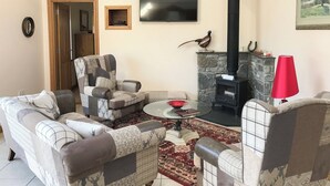 Un salon avec une cheminée, deux fauteuils, un canapé et une table basse.