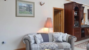 Un salon avec un canapé, une lampe, un tableau et un meuble en bois.