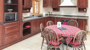 Une cuisine avec des meubles de rangement en bois, un four à micro-ondes, un évier et une table à manger avec des chaises.
