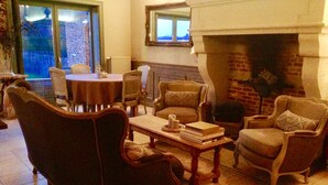 A cozy living room with a fireplace, comfortable seating, and a dining area. - B&B Silentium (Tielt-Winge)