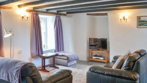 A living room with a sofa, a television on a stand, a lamp, and a window with curtains. - 2 bedroom accommodation in Trebarwith, Delabole (Trebarwith, Delabole)