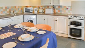 A kitchen with white cabinets, a microwave, a toaster, and a stove. - 2 bedroom accommodation in Trebarwith, Delabole (Trebarwith, Delabole)