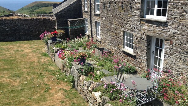 A stone house with a garden, a small table, and chairs. - 2 bedroom accommodation in Trebarwith, Delabole (Trebarwith, Delabole)