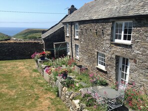 A stone house with a garden, a small table, and chairs. - 2 bedroom accommodation in Trebarwith, Delabole (Trebarwith, Delabole)