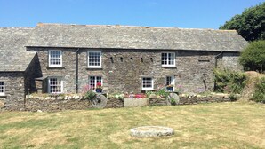 A stone building with multiple windows and a well-maintained lawn. - 2 bedroom accommodation in Trebarwith, Delabole (Trebarwith, Delabole)