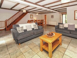 A living room with a sofa set, a wooden coffee table, and a staircase.