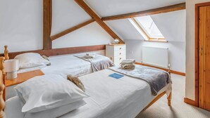 A room with two beds, a wooden ceiling, a skylight, a radiator, and a wooden door. - 3 bedroom accommodation in Catfield (Catfield)