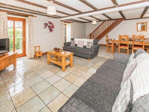 A living room with a sofa, a coffee table, a television, and a dining area with chairs and a table.