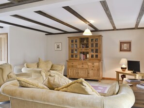 A living room with a sofa, a wooden cabinet, a lamp, and a television. - 3 bedroom accommodation in Catfield (Catfield)