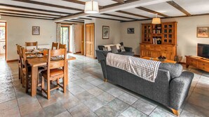 A spacious living area with a dining table, chairs, a sofa, and a wooden cabinet. - 3 bedroom accommodation in Catfield (Catfield)